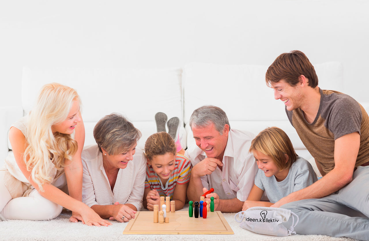 Eine große Familie schaut gemeinsam auf das Systembrett. Alle haben viel Saß bei der Aufstellungsarbeit